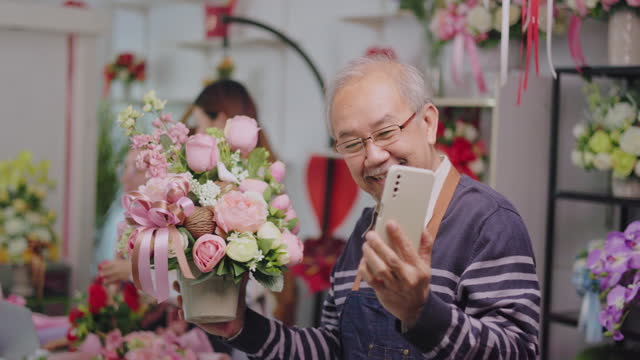 Asian young  female florist worker and senior man shop owner arranging blossoms bouquet together in valentine,  in colorful flower store.