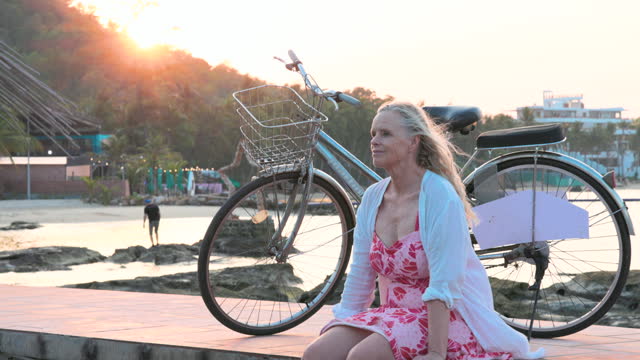Mature woman relaxes with bicycle on pier