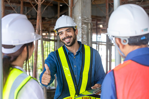 Engineering manager is giving thumbs up to contractor and foreman in meeting and consulting at construction building for inspection in real estate development project industry and quality control