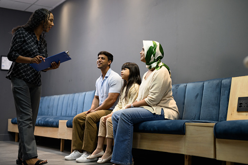 Nurse greeting family sitting waiting in hospital waiting room