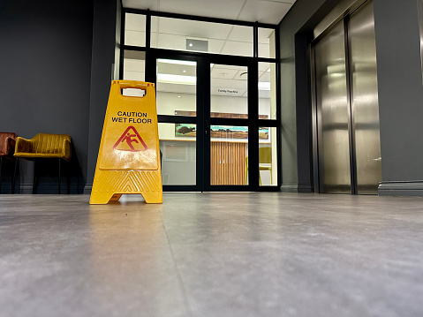 Caution wet floor sign at glass doors to building entrance