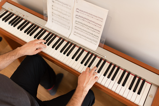 Adult man is playing the digital piano at home