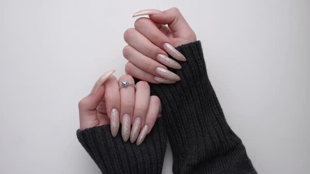 Beautiful hands of a young woman with pearl colored  manicure on nails