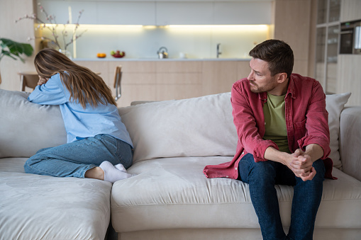 Couple relations, man woman offended each other. Wife crying turning away sitting on couch, husband talking with her. Relationships crisis, marital discord, family quarrel, offended spouses concept.