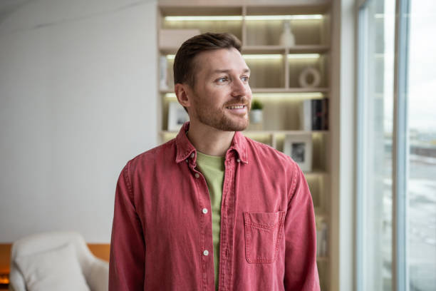 istock Smiling relaxed man looking at window in new home apartment thinking about future, daydreaming. 1967070476