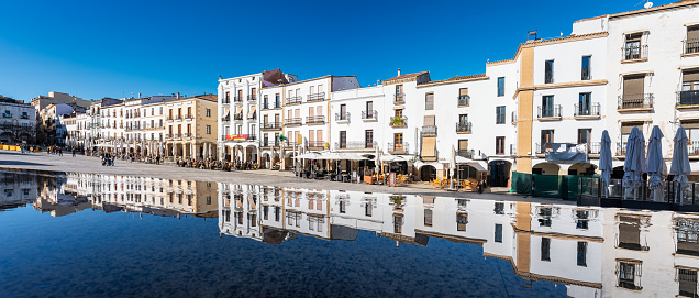 Facades of white houses that are reflected in the water of the city of Caceres, Extremadura