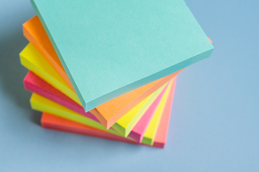 Multicoloured paper sticky notes on blue background