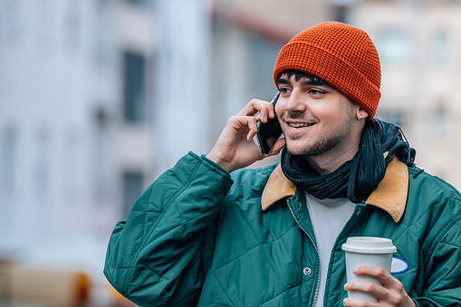 young man on the street talking on the mobile phone in winter with warm clothes