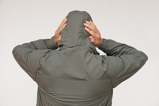 Back view of man wears hoodie, uses his hands to cover ears. Concept, don't want to listen or hear anything. Distressed by noise. Avoid listening to noise of complains or negative words.