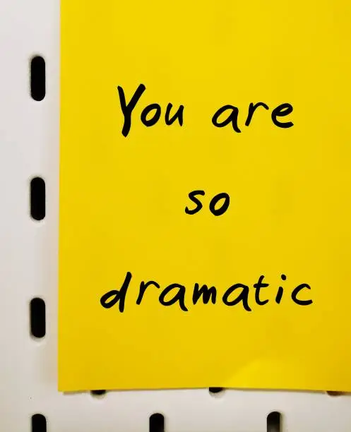 Handwritten on yellow stick note YOU ARE SO DRAMATIC - gaslighting way to accuse or emotional abuse others to question their beliefs or doubt their perception and become distressed