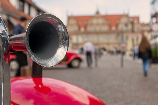 metal horn on red car fender on background of city streets