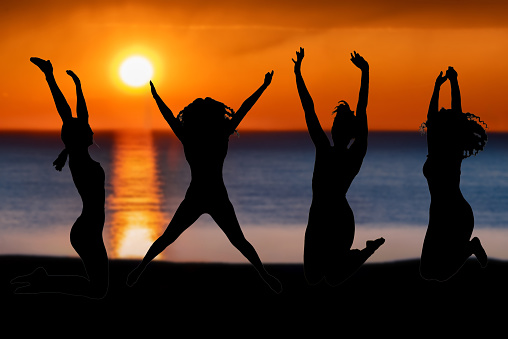 Young friends women jumping for joy on the beach