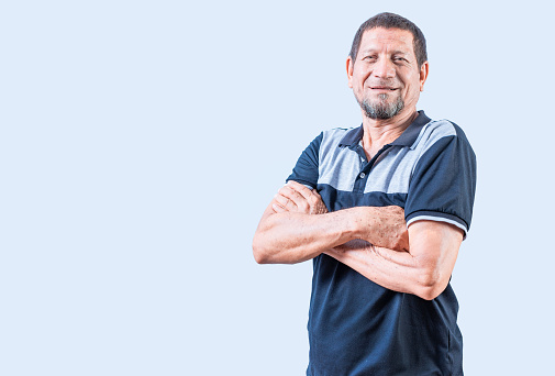 Smiling latin old man with arms crossed, casual on isolated background. Portrait of smiling senior man with arms crossed isolated