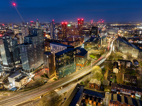 Aerial image of Manchester skyline over Mancunian Way showing light trails from the traffic below and new urban development.