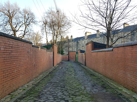 A minor street, a single lane road between tenement houses, Glasgow Scotland England UK