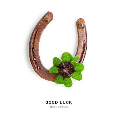 Old horseshoe and four leaf clover isolated on white background. Good luck concept. St. Patrick day greeting card. Top view, flat lay. Design element