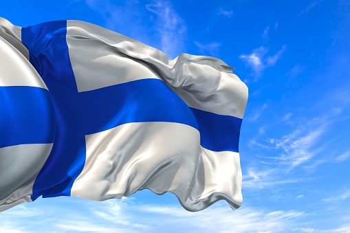 The national flag of Finland with fabric texture waving in the wind on a blue sky. 3D Illustration