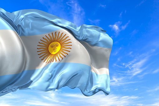 The national flag of Argentina with fabric texture waving in the wind on a blue sky. 3D Illustration