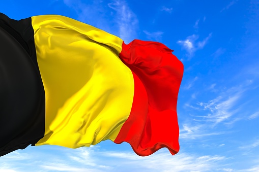 The national flag of Belgium with fabric texture waving in the wind on a blue sky. 3D Illustration