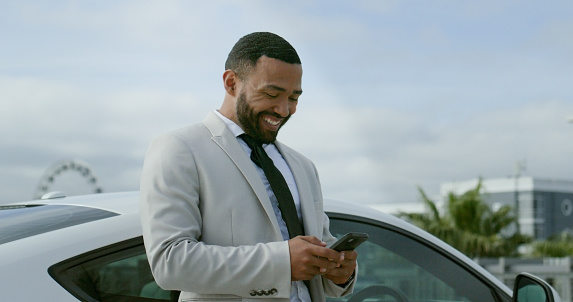 Businessman, cellphone and message by car for travel, transport and technology for online connection in city. Young person, happy and smartphone for communication, text and trip to company in town
