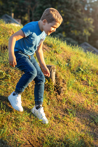 Smiling little boy in motion climbing down a steep slope.