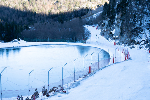 skiers pass by a frozen lake on a ski slope in the french pyrenees. ski resort of Arette la pierre du saint martin.