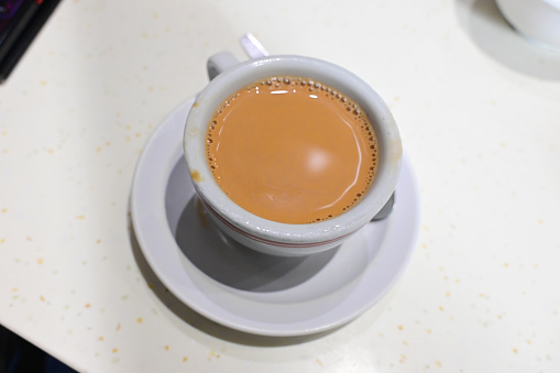 A cup of milk tea on saucer on a table