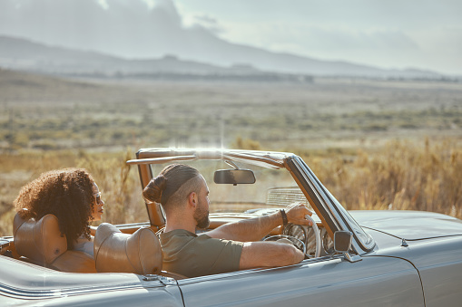 Car, back view or couple driving on road trip on holiday together with love, care and adventure. Journey, interracial or people in countryside or motor transport for vacation for freedom or honeymoon