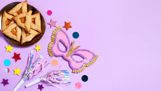 purim carnival background with traditional cookies, costume accessories and decor on pastel violet - purim high angle view cookie food 뉴스 사진 이미지