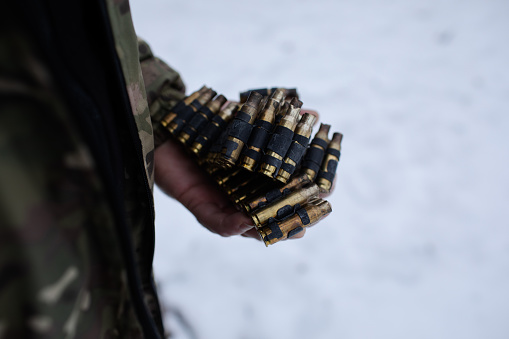 Ukrainian army. used cases in machine gun tape in the hand of the Ukrainian military in winter uniform