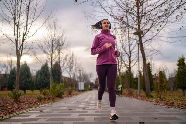istock Young woman jogging in public park, outdoors at night. 1967525462
