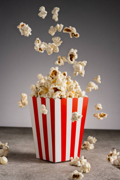 istock Popcorn in red and white striped paper box isolated on grey background 1967535047