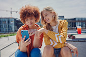 Skater women friends, phone and park with reading, point and meme with discussion for online gossip. Girl, gen z people and smartphone for chat, memory and funny video on social network app in city