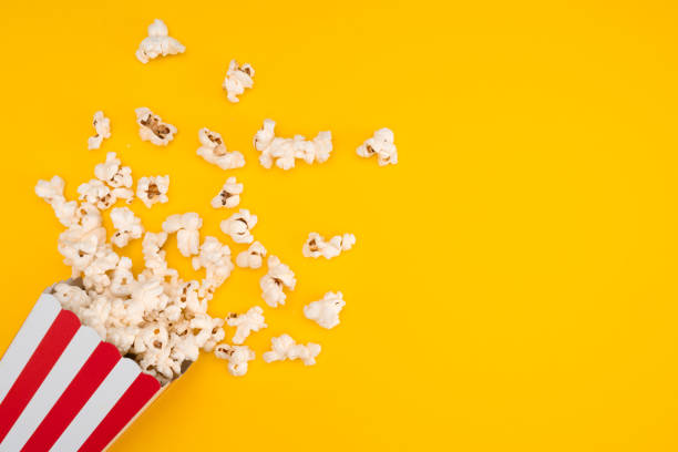 istock Popcorn in red and white striped paper box isolated on yellow background 1967535630