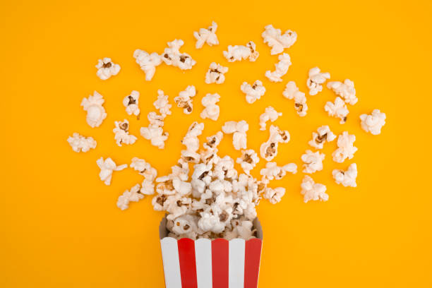 istock Popcorn in red and white striped paper box isolated on yellow background 1967535669