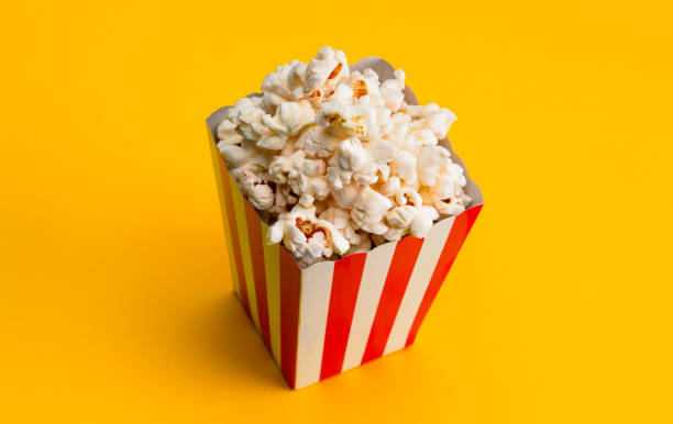 istock Popcorn in red and white striped paper box isolated on yellow background 1967535720