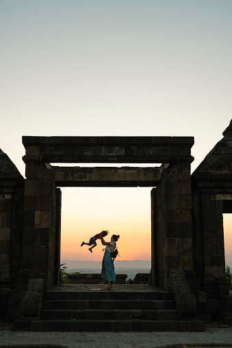 Chinese mother carrying her son hand when climbing stair on  Ratu Boko Temple, Yogyakarta. Ratu Boko is archaeological site known to modern Javanese as Kraton Ratu Boko or Ratu Boko's Palace.