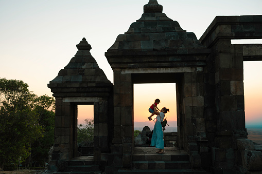 Chinese mother carrying her son hand when climbing stair on  Ratu Boko Temple, Yogyakarta. Ratu Boko is archaeological site known to modern Javanese as Kraton Ratu Boko or Ratu Boko's Palace.