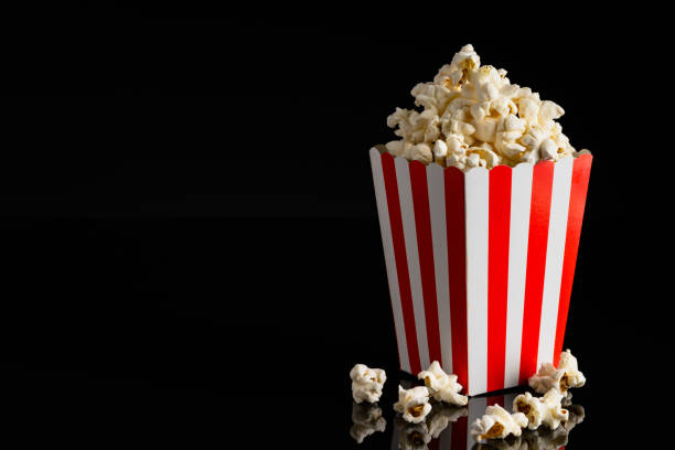istock Popcorn in red and white striped paper box isolated on black background 1967536118