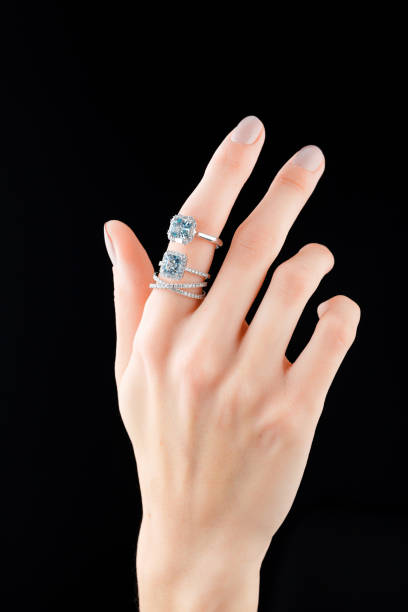 istock Beautiful female hand with gold ring with diamonds and emerald on black background 1967540853