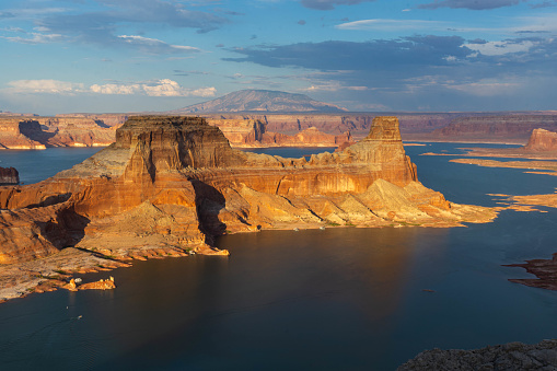 Lake Powell and vibrant sandstone dominate the foreground with clouds in the background.