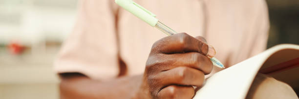 istock Close-up of young african student's hand taking notes, Panorama 1967546377