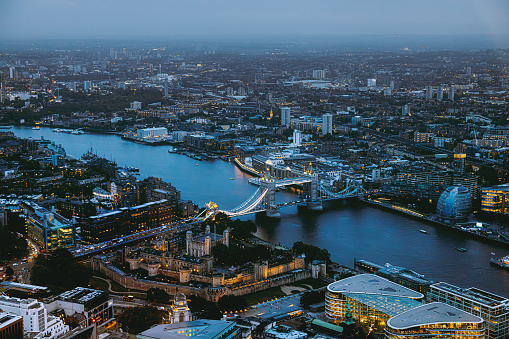 Panoramic aerial night view after sunset to the cityscape of London with Tower Bridge and the illuminated skyscrapers of the city during dusk in the United Kingdom