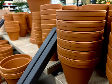 Stacks of terracotta clay pots for plants for sale at a garden store.
