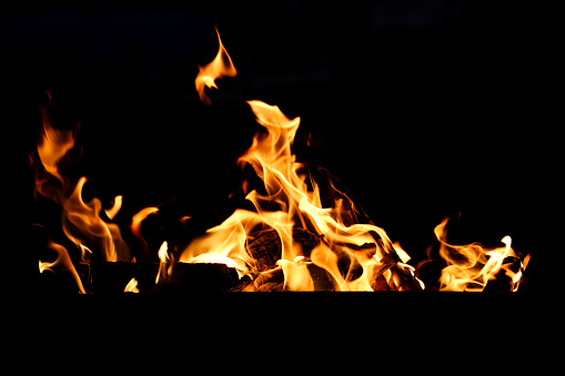 Stock photo showing close-up view of large flames on a barbecue at an outdoor beach restaurant, which has been lit in preparation of cooking seafood.