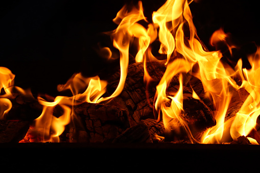 Stock photo showing close-up view of large flames on a barbecue at an outdoor beach restaurant, which has been lit in preparation of cooking seafood.