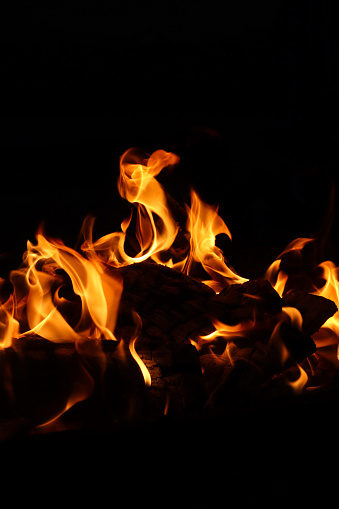 Stock photo showing close-up view of large flames on a barbecue at an outdoor beach restaurant, which has been lit in preparation of cooking seafood.