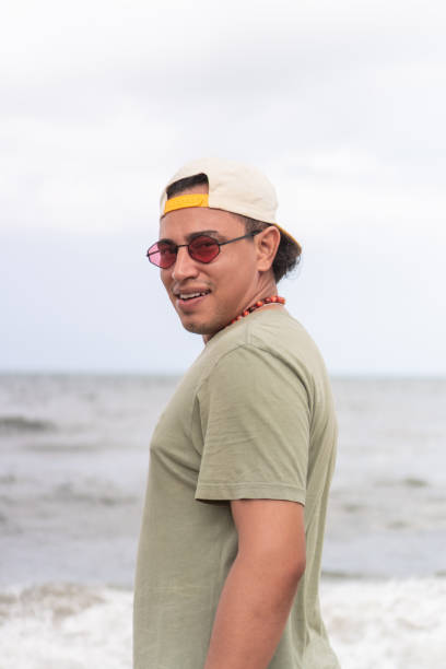 istock Latin man with sunglasses at the beach, looking over shoulder. 1967655046