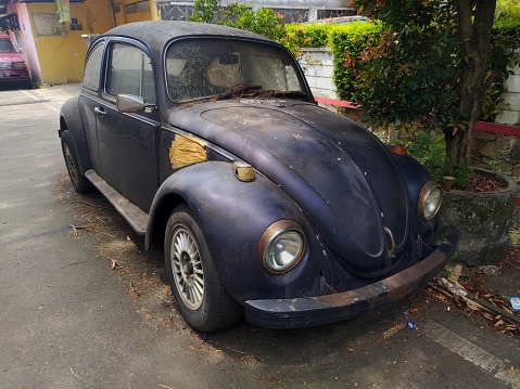 Bandung, Indonesia - January 28, 2024 : Vintage abandoned Volkswagen Beetle car parked on the side of the street in Bandung, Indonesia
