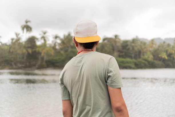 Person in reflective moment overlooking calm tropical lake.